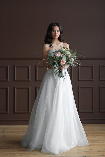 Donna bella sposa in abito da sposa elegante con bouquet di fiori