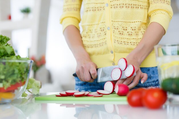 donna bionda attraente che prepara insalata a casa