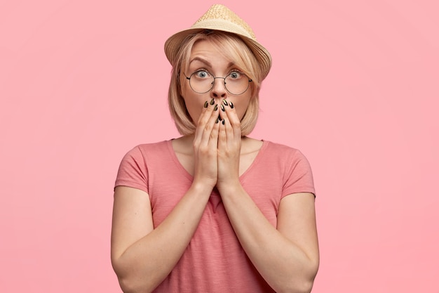 Donna bionda che indossa cappello e maglietta rosa