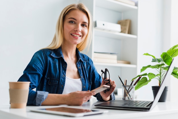 Donna bionda che lavora con smartphone e occhiali