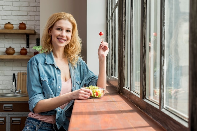 Donna bionda che mangia un&#39;insalata