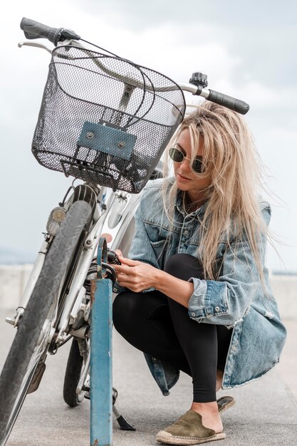 Donna bionda che mette una serratura della bici