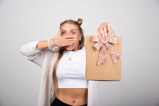 Donna bionda che mostra scatola regalo