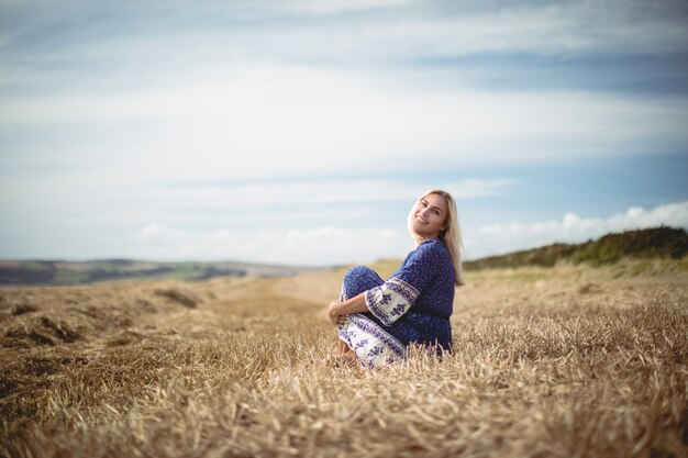 Donna bionda che si siede nel campo