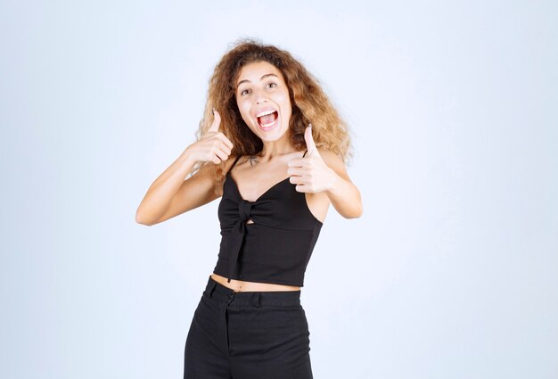 Donna bionda con i capelli ricci che mostrano un buon segno con la mano.