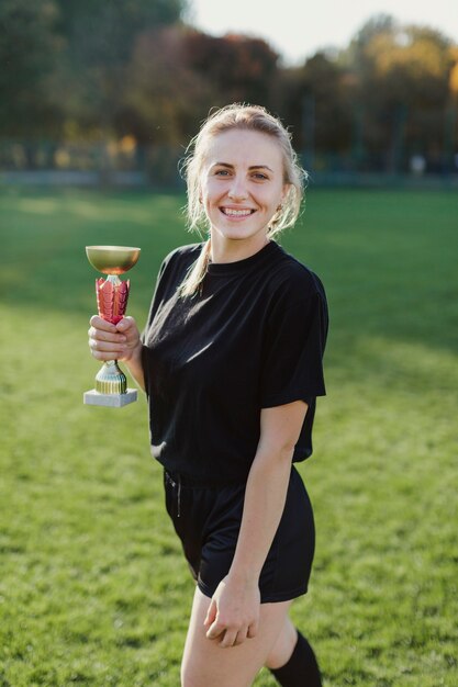 Donna bionda graziosa che tiene un trofeo