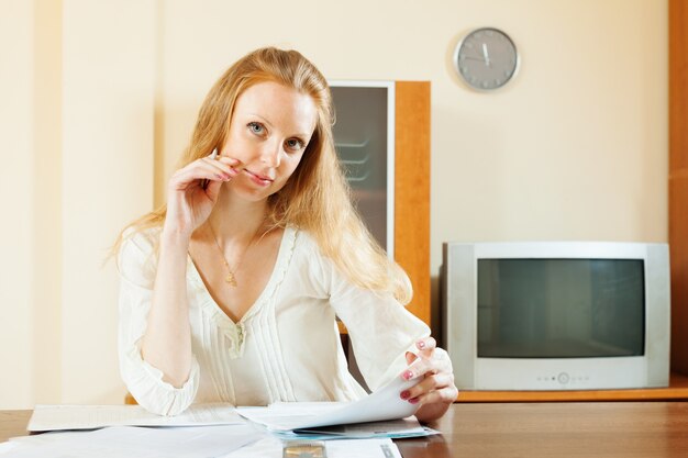 Donna bionda guardando documenti finanziari a tavola