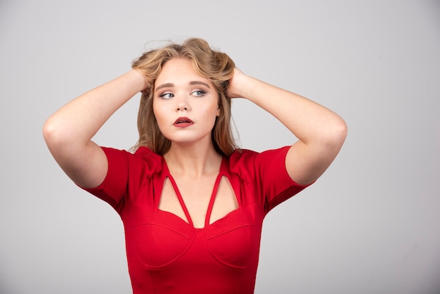 Donna bionda in abito rosso che tiene i suoi capelli.