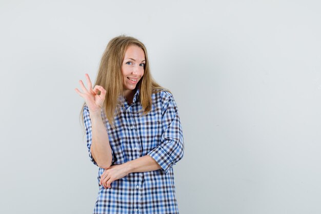 Donna bionda in camicia che mostra gesto giusto e che sembra allegra,