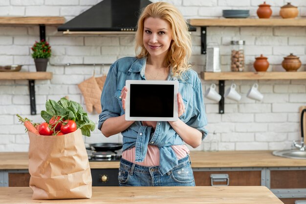 Donna bionda in cucina con un tablet