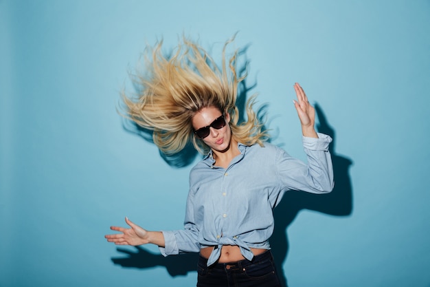 Donna bionda insolita in camicia e occhiali da sole che guarda l'obbiettivo