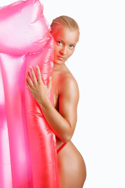 Donna bionda sessuale che posa con un materasso ad acqua rosa.