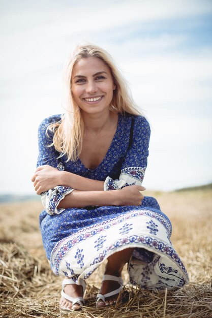 Donna bionda sorridente che si accovaccia nel campo