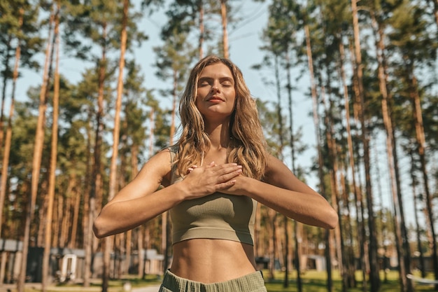 Donna bionda sveglia che pratica yoga fuori e sembra rilassata