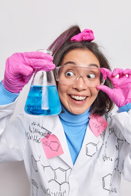 donna biotecnologa conduce esperimento guarda felicemente riceve blueliquid dopo aver miscelato i reagenti vestiti in pose uniformi su white