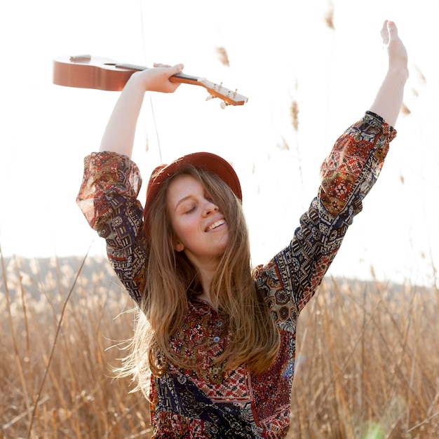 Donna bohémien felice che posa mentre tenendo ukulele