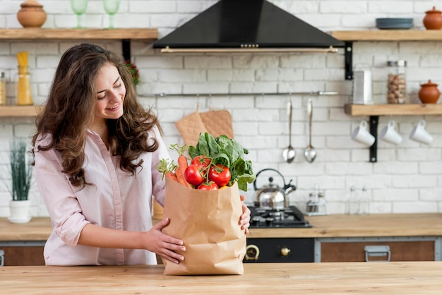 Donna bruna con un sacchetto di carta pieno di cibo sano