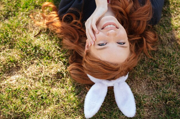 Donna capa rossa che indossa le orecchie del coniglietto di pasqua all'aperto