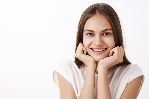 Donna carina appoggiato la testa sui palmi e guardando con sguardo ammirato sorridente ampiamente sentendosi felice e divertito