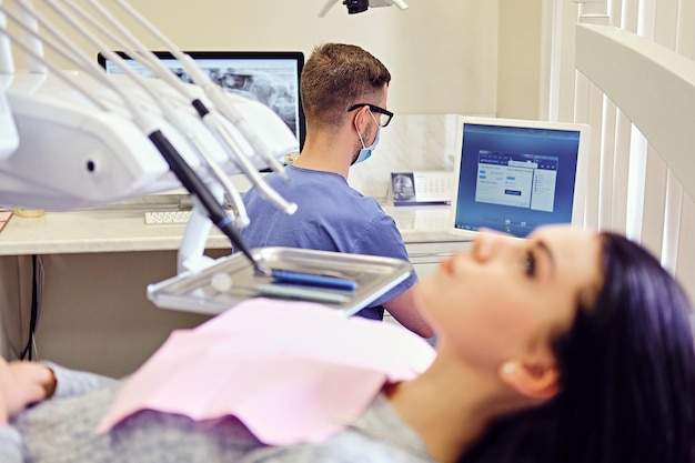 Donna castana attraente su una sedia del dentista in una stanza di stomatologia.