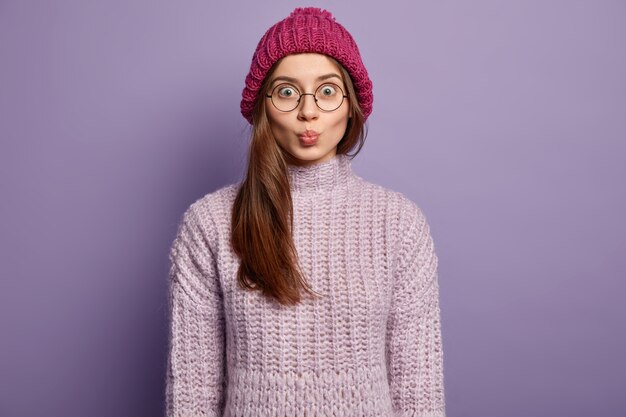 Donna castana che indossa cappello e maglione lavorato a maglia