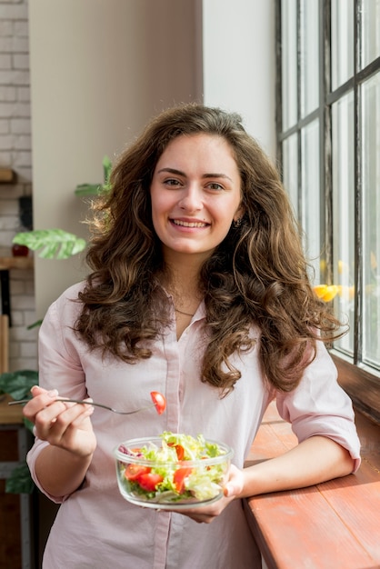 Donna castana che mangia un&#39;insalata