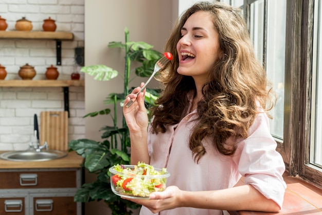 Donna castana che mangia un&#39;insalata