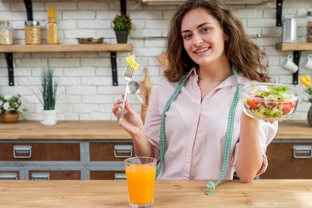 Donna castana che mangia un&#39;insalata