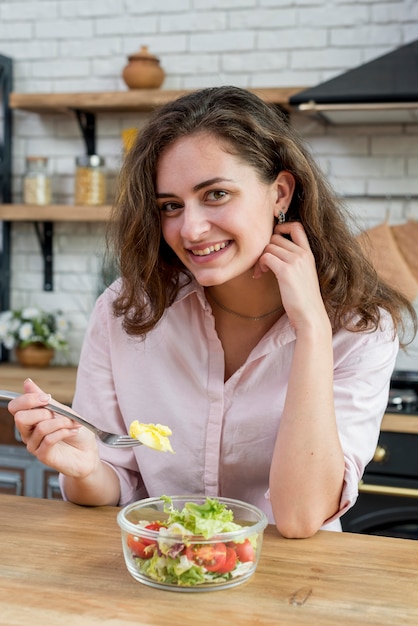 Donna castana che mangia un&#39;insalata