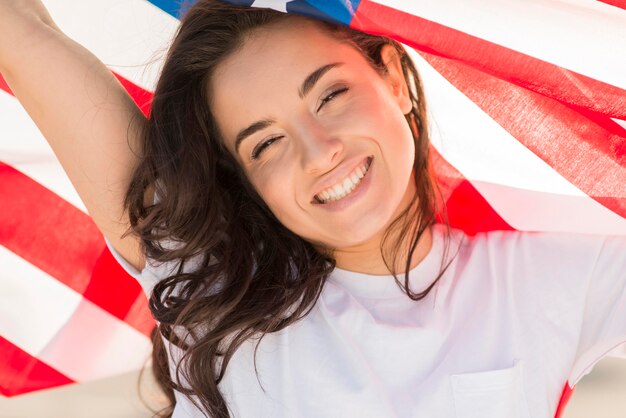 Donna castana del primo piano che tiene la grandi bandiera e sorridere degli SUA