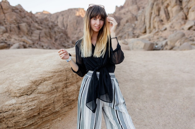 Donna castana elegante che posa nelle dune di sabbia del deserto egiziano.