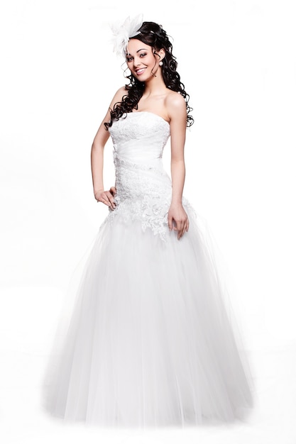 Donna castana felice felice della bella sposa in vestito da sposa bianco con l'acconciatura e trucco luminoso integrale nel retro stile