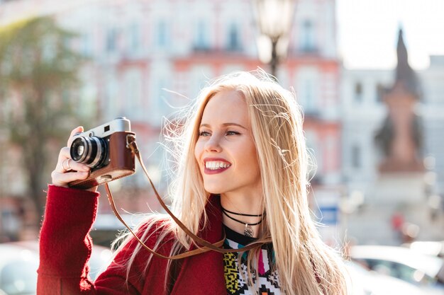 Donna caucasica abbastanza giovane che cammina all'aperto che tiene macchina fotografica