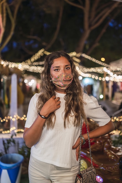 Donna caucasica abbronzata che indossa una maschera floreale in un parco di divertimenti