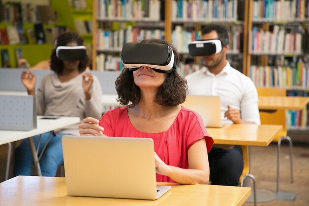 Donna caucasica allegra che indossa la cuffia avricolare di VR