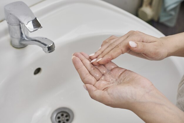 Donna caucasica che pratica una corretta igiene lavandosi le mani sopra un lavandino