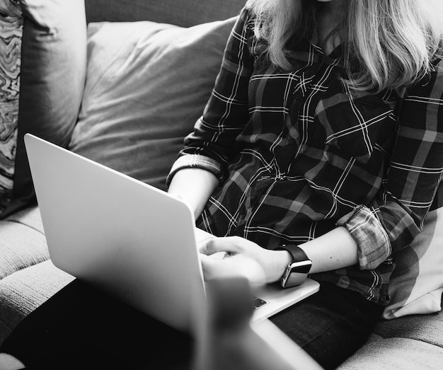 Donna caucasica che utilizza computer portatile sul divano