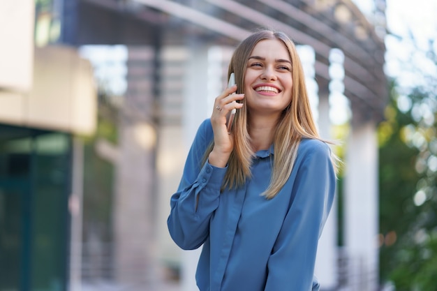 Donna caucasica di affari che parla dal caffè della tenuta del telefono per andare. Una donna europea di successo, parlando al telefono, in piedi su un moderno edificio per uffici