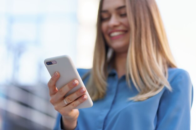 Donna caucasica di affari che parla dal caffè della tenuta del telefono per andare. Una donna europea di successo, parlando al telefono, in piedi su un moderno edificio per uffici