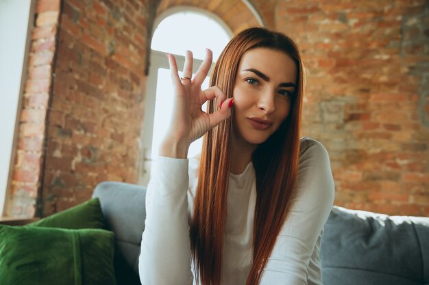 Donna caucasica isolata sul fondo del muro di mattoni a casa.