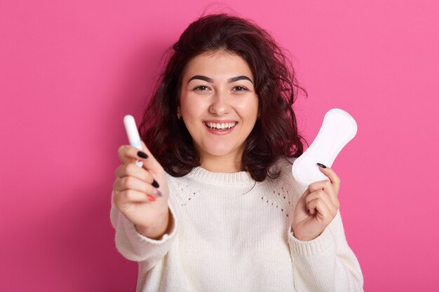 Donna caucasica soddisfatta felice che tiene diversi tipi di prodotti per l'igiene femminile