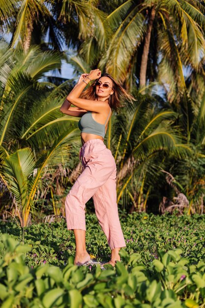 donna caucasica tatuata in pantaloni rosa e top corto verde alla moda