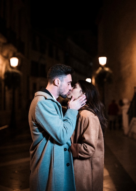 Donna che abbraccia e bacia con il giovane sulla passeggiata di notte