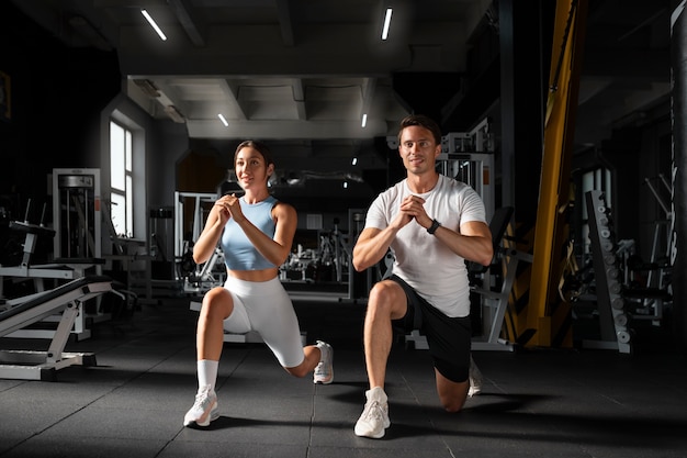 Donna che aiuta l'uomo in palestra