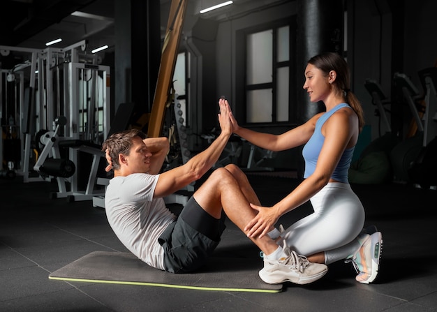 Donna che aiuta l'uomo in palestra