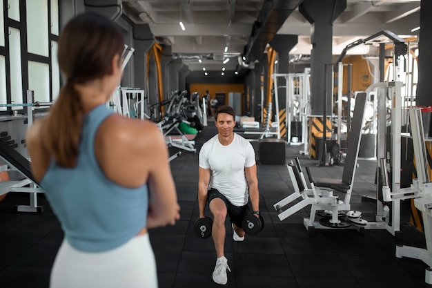 Donna che aiuta l'uomo in palestra