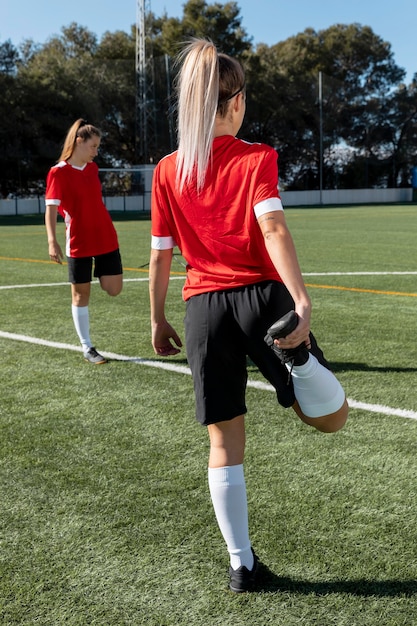 Donna che allunga la gamba sul campo di calcio a pieno tiro