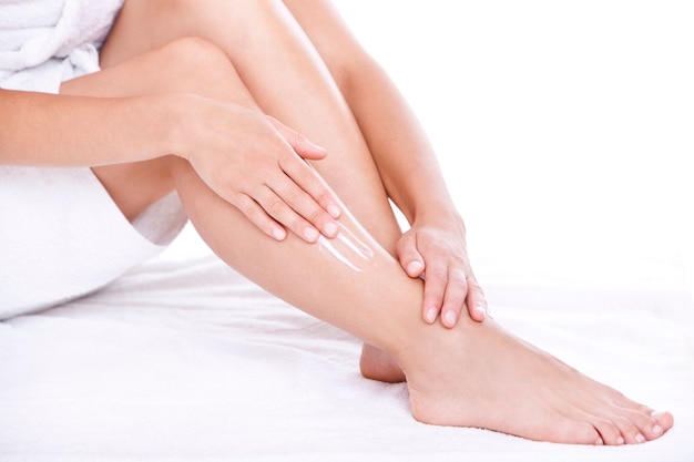 Donna che applica la crema idratante sulle gambe