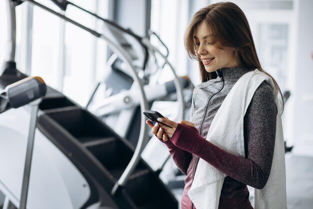 Donna che ascolta musica e acqua potabile in palestra