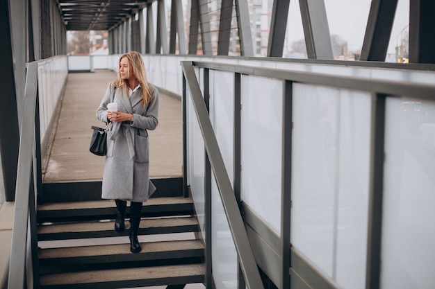 Donna che attraversa il ponte e beve caffè